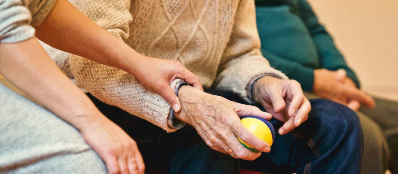 Starszy człowiek ugniata piłkę w ręku.